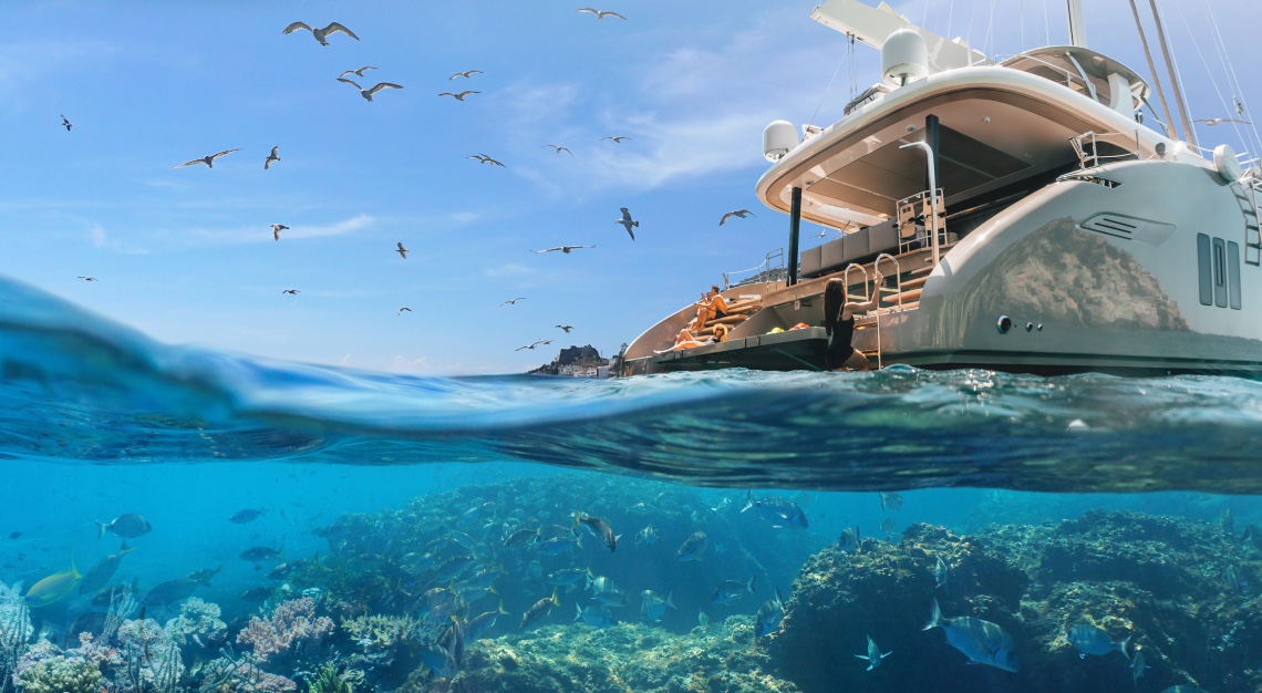 underwater marine life with two people sitting atop a yacht