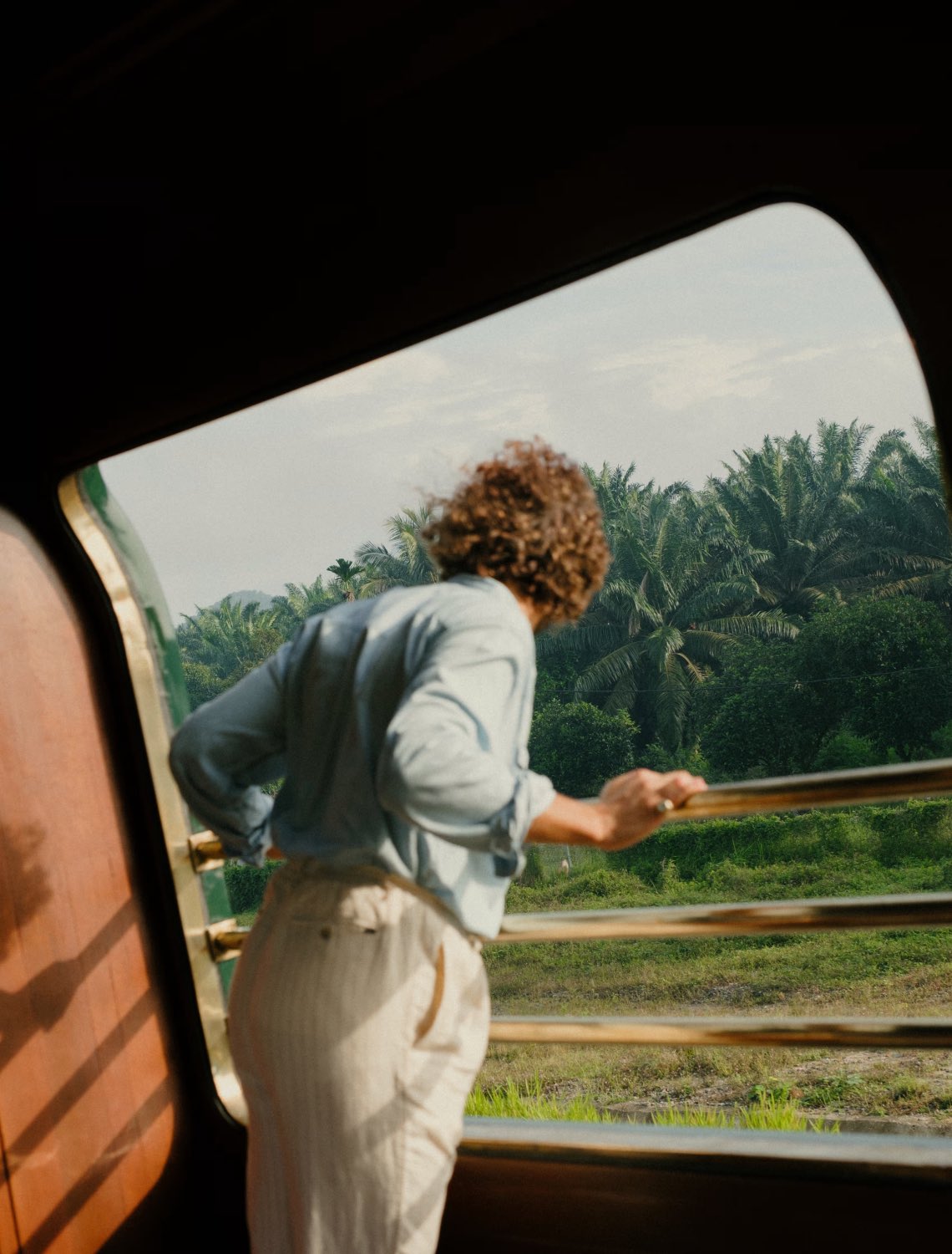 a woman peering over the guardrails on the Belmond Eastern & Oriental Express