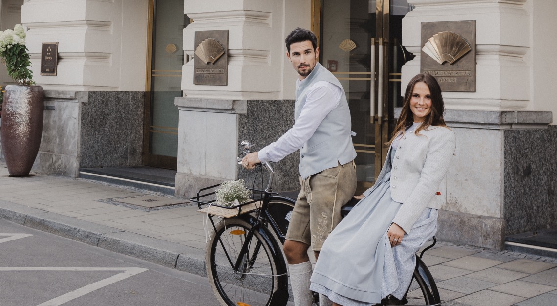 a man and a woman dressed in traditional Bavarian clothing in front of Mandarin Oriental, Munich