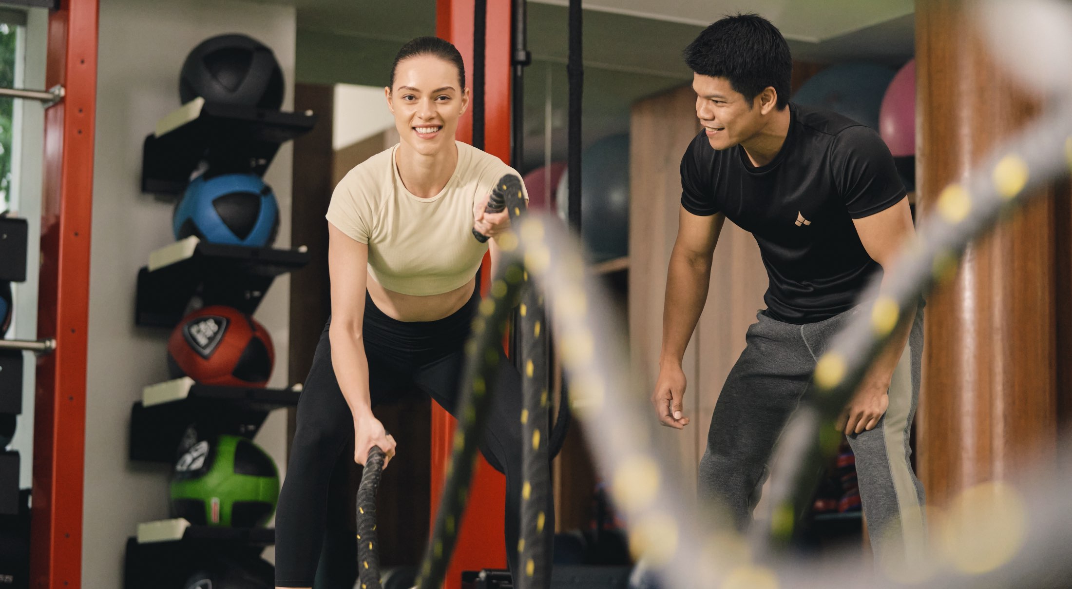 a woman exercising with a male fitness trainer beside her