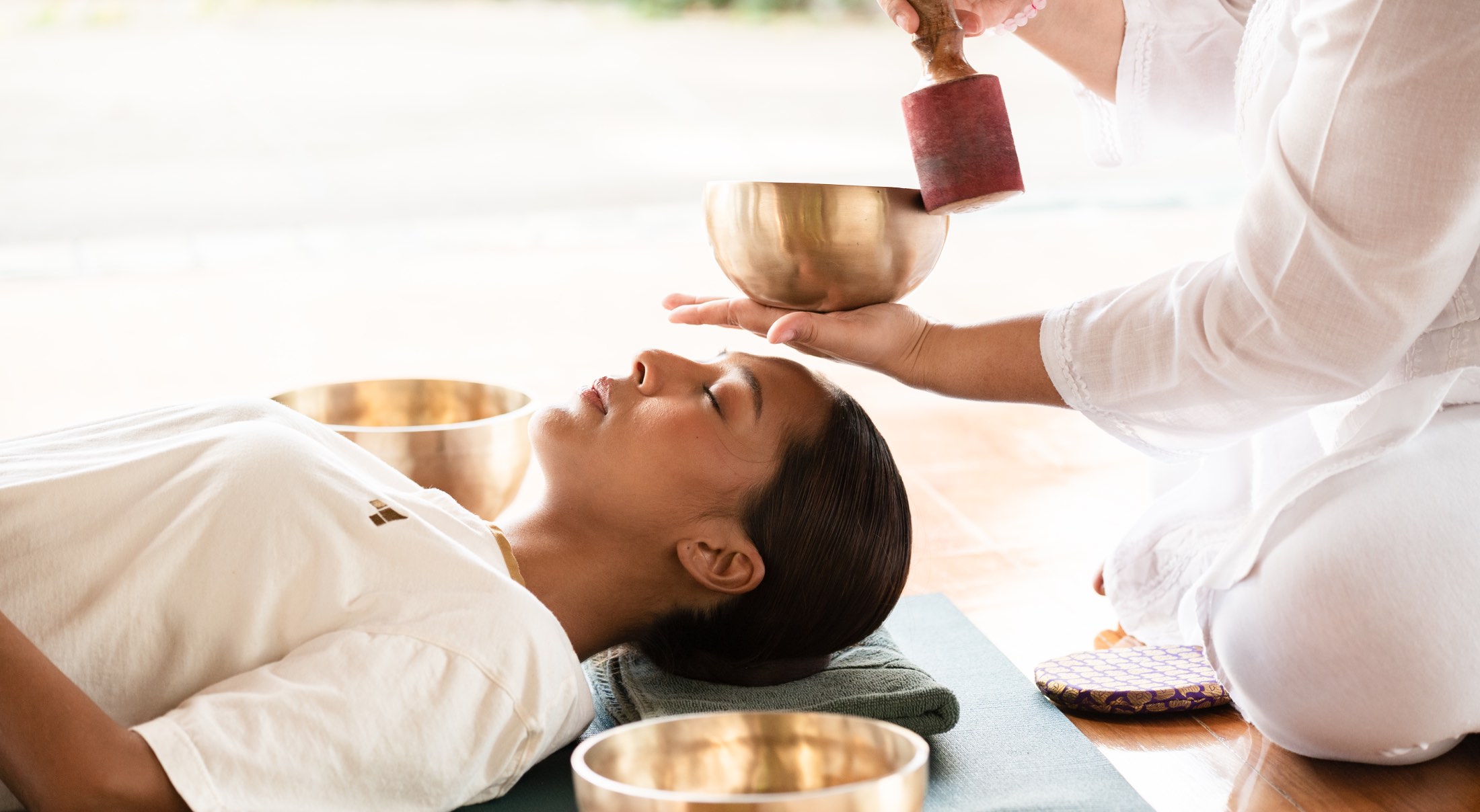 a lady lying down with a Tibetan singing bowl being struck above her