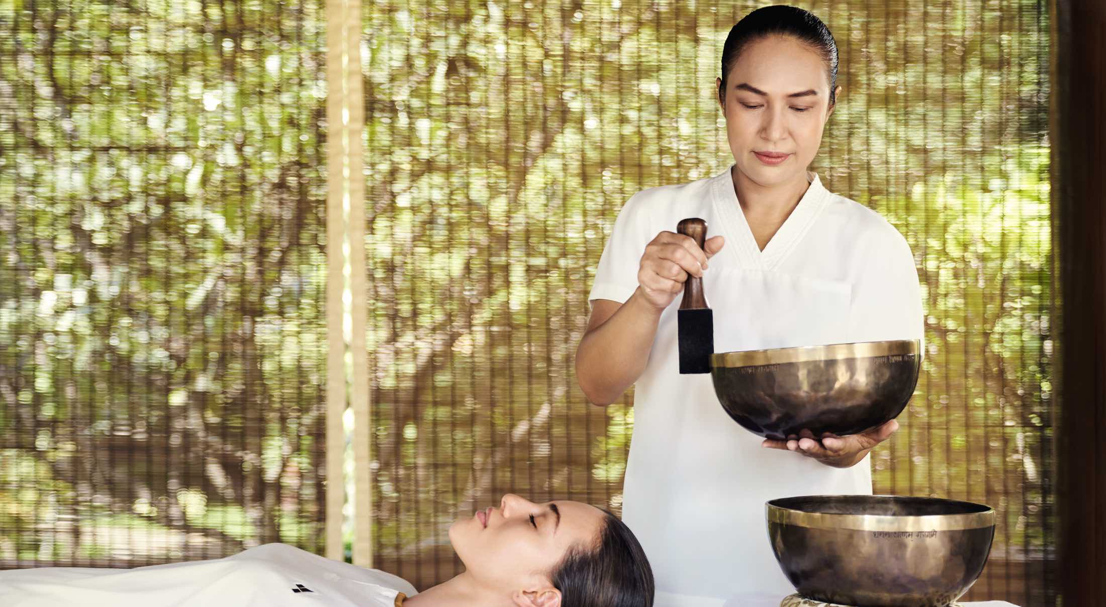 a masseuse hitting a tibetan striking bowl